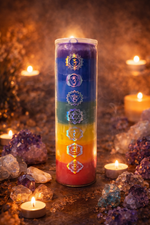 Load image into Gallery viewer, Colorful candle with chakra symbols surrounded by crystals and candles on a dark background
